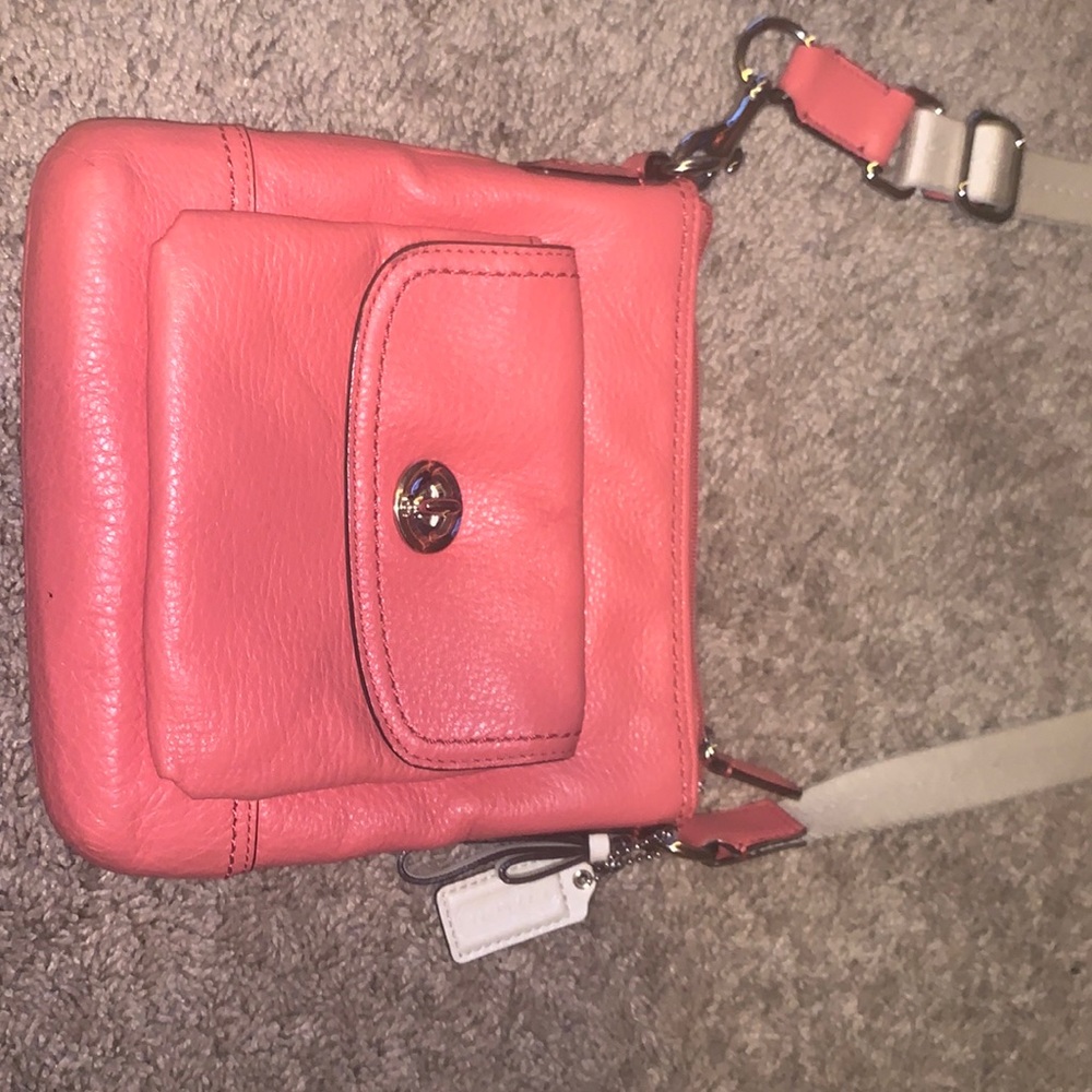 Coach crossbody bag, salmon color with beige strap that’s adjustable.